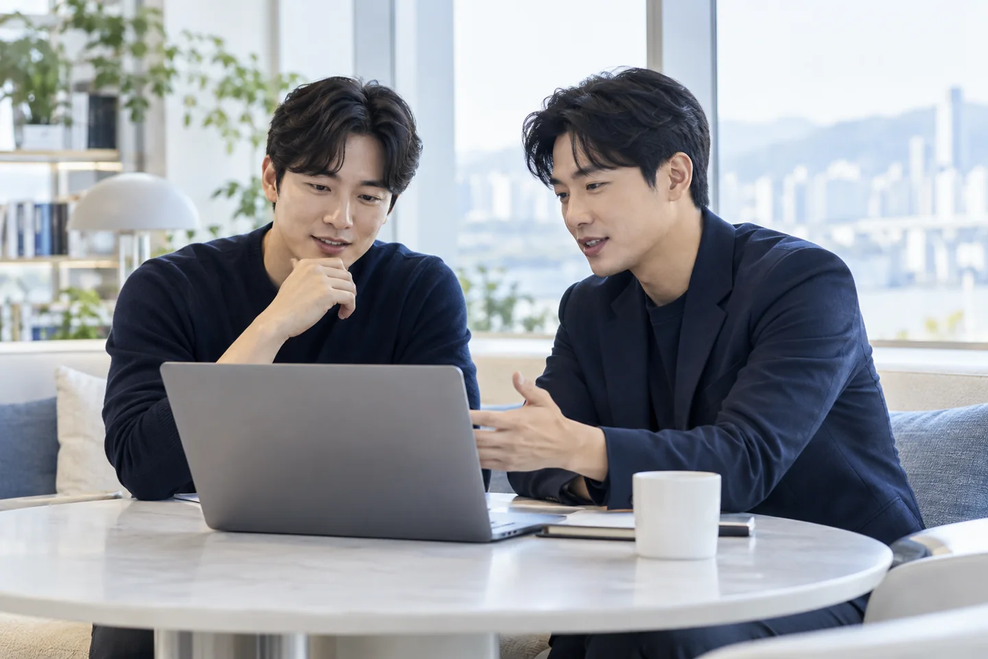 노트북을 보며 근무 조건을 함께 살펴보는 성인 남성 두 명의 연출 이미지